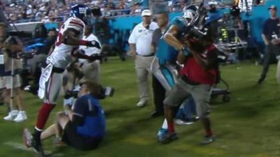 Antrel Rolle and Greg Olsen collide with two cameramen