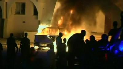 Protesters watch as a car burns in Benghazi