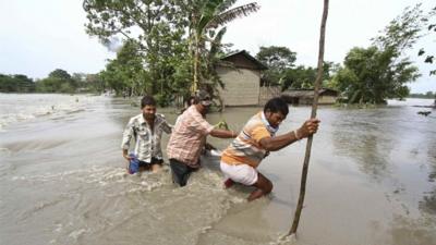 Villagers cross a flooded road at Lachi Bishnupur village in the northeastern Indian state of Assam September 22, 2012.