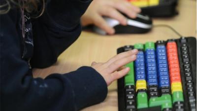 School girl working in class on a computer keyboard