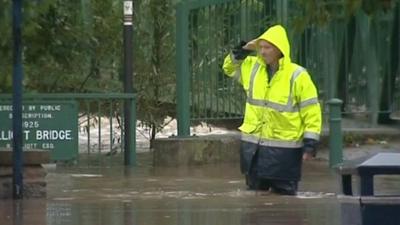 Man walks through flood water in Morpeth