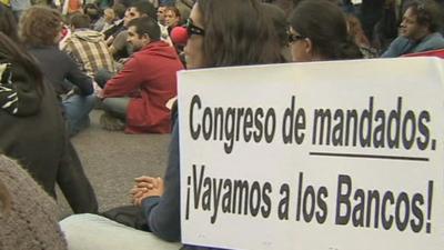 Young protesters with placards staging a sit-in protest in central Madrid