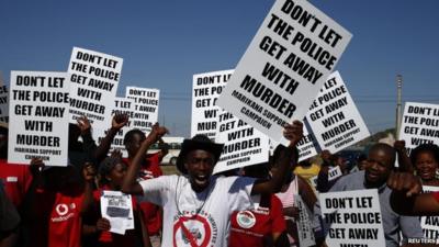 Demonstrators wave placards during a site inspection by the judicial commission