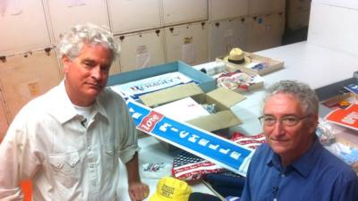 Larry Bird and Harry Rubenstein standing alongside materials they picked up at political rallies in the US