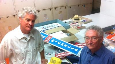Larry Bird and Harry Rubenstein standing alongside materials they picked up at political rallies in the US