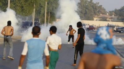 Protesters take cover from tear gas fired by riot police during clashes in the Bahraini capital of Manama.