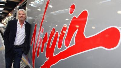 Sir Richard Branson standing next to a Virgin train