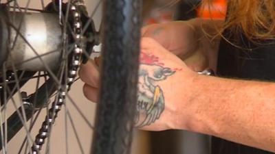 Tattooed hands working on bike wheel