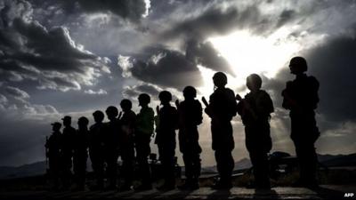 Afghan policemen stand guard for a debriefing during an exercise