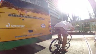 Man on bike behind bus in Hong Kong