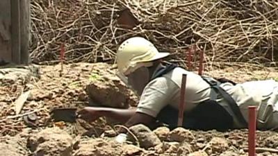 Woman digs around a landmine