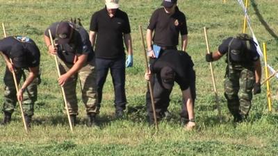 Police officers searching a field near the farmhouse