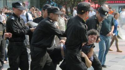 Protester carried by riot police