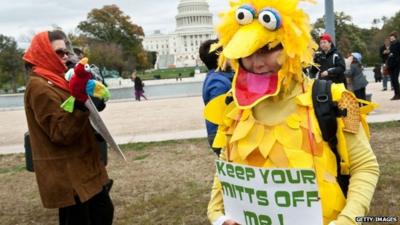 A woman wearing a costume of Sesame Street character Big Bird holds a sign in support of public broadcasting during the "Million Puppet March" in Washington