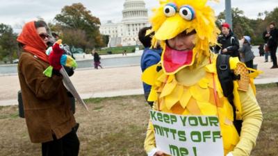 A woman wearing a costume of Sesame Street character Big Bird holds a sign in support of public broadcasting during the "Million Puppet March" in Washington