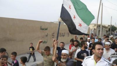 Residents hold an opposition flag during a protest against Syria's President Assad in Sermada