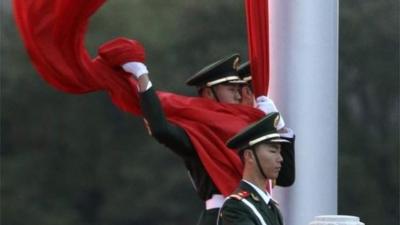 Chinese policeman holding flag in Tiananmen Square