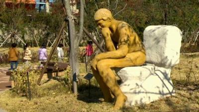 Sculpture of man on toilet