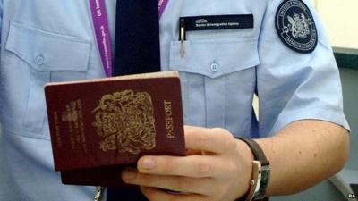 Immigration officer checking a passport at Heathrow Airport