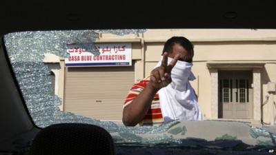 Man inspects damage to a car in Bahrain