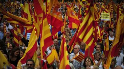 People opposed to the independence of Catalonia hold Catalan and Spanish flags during the holiday known as Dia de la Hispanidad