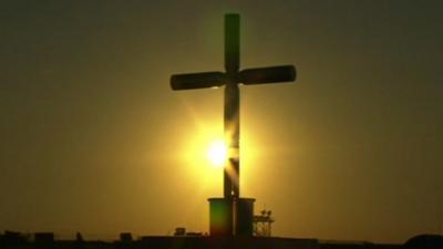 Sun sets behind cross