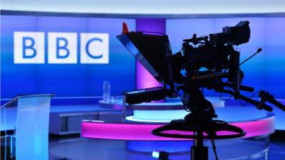 Silhouette of camera against Newsnight studio and BBC logo