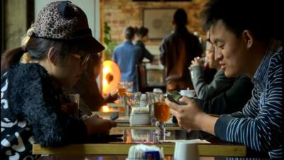 Two young people in China using mobile phones