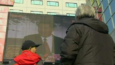 Beijing residents looking at a giant TV screen broadcast of the announcement