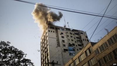 Smoke billows as debris flies from the explosion at the local Al-Aqsa TV station in Gaza City on November 18, 2012