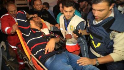 Palestinian medical workers wheel a wounded Palestinian journalist on a stretcher to Al-Shifa hospital in Gaza City