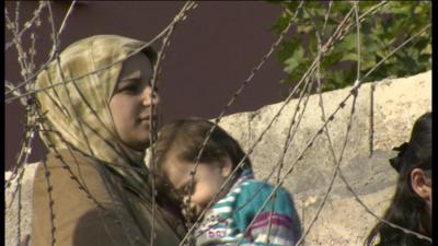 Woman and child by barbed wire fence