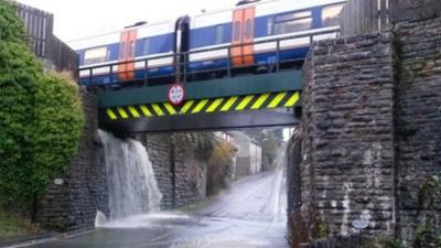 Water cascading off railway line onto the road below