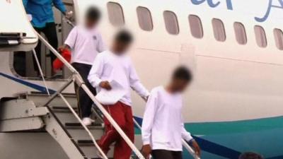 Unidentified asylum seekers, stepping off plane