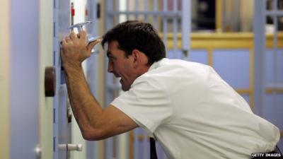 A police officer inspects a cell at a police station custody suite