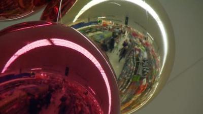 Supermarket aisles reflected in Christmas baubles