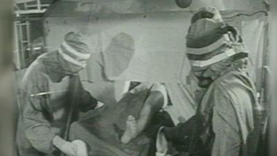 Black and white archive footage of hip replacement operation