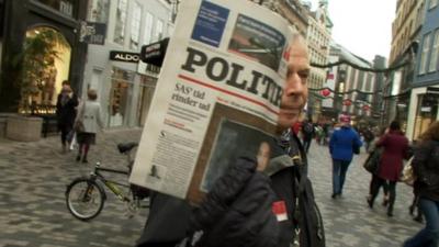 A Danish newspaper seller holding newspaper