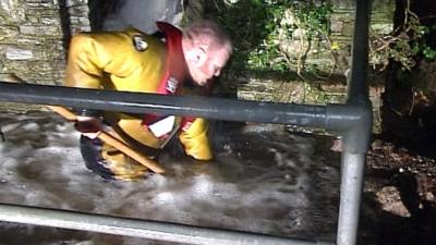 Man clearing flooded drain