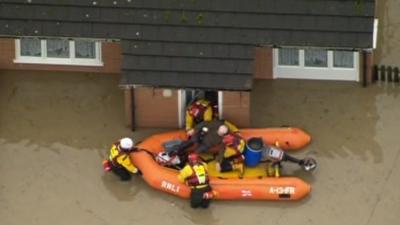 Rescue boat helping someone from their flooded house