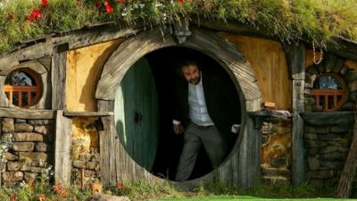 Director Sir Peter Jackson emerges from from a Hobbit house