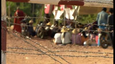 Seated protesters behind barbed-wire fence