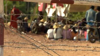 Seated protesters behind barbed-wire fence