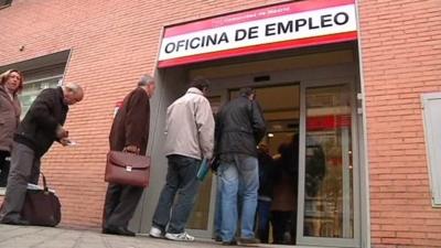 Unemployed people queue to get into a job centre in Spain