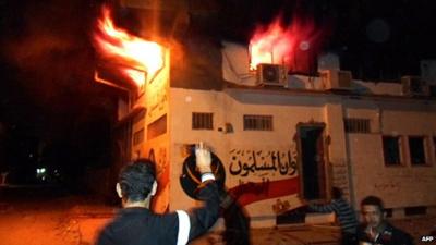 Egyptian protesters stand outside the burning office of the Muslim brotherhood in Ismailia