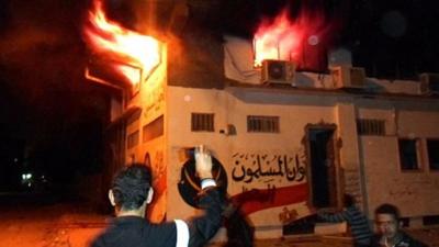 Egyptian protesters stand outside the burning office of the Muslim brotherhood in Ismailia