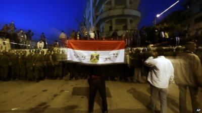 Protester with Egyptian flag near line of security forces