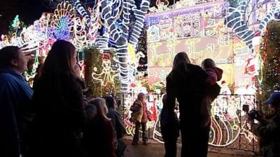 People looking at a house in Melksham covered in Christmas lights