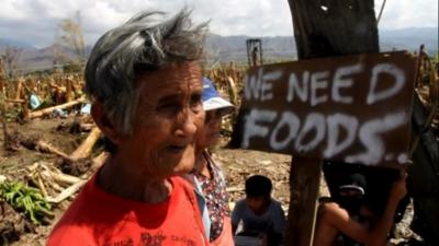 Woman with sign saying "We need food"