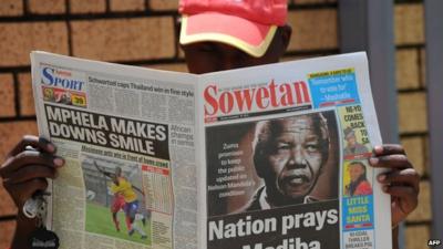 Man reads newspaper with story about Nelson Mandela in hospital